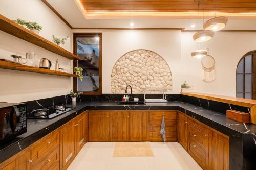 a kitchen with wooden cabinets and black counter tops at Green Mutiara Jimbaran in Jimbaran