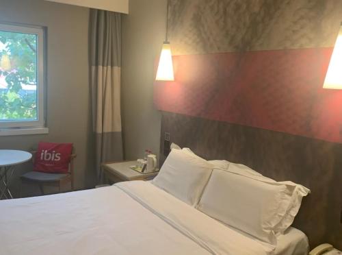 a hotel room with a bed with two pillows at Ibis Tianjin Development Zone TEDA Third Avenue in Binhai