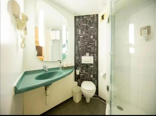 a bathroom with a sink and a toilet and a mirror at Ibis Tianjin Development Zone TEDA Third Avenue in Binhai