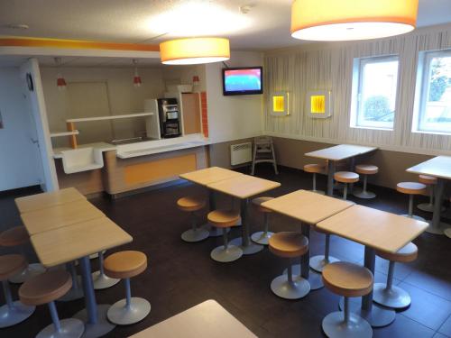 une salle d'attente vide avec des tables et des tabourets dans l'établissement ibis budget Lille Wasquehal, à Wasquehal