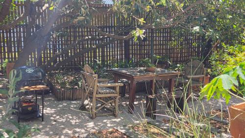 a table and chairs in a garden with a fence at Noordhoek Beach Cabin in Noordhoek