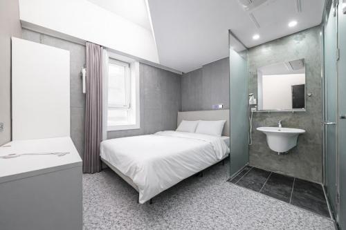 a bedroom with a bed and a sink and a mirror at Connected Hotel Guro in Seoul