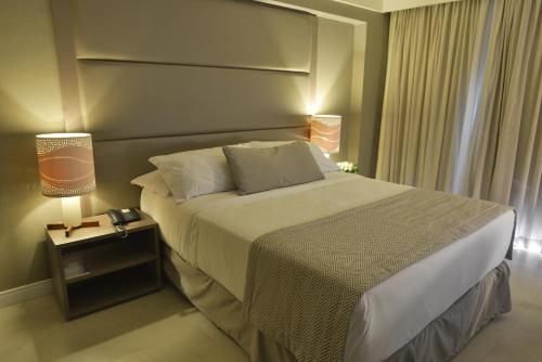 a bedroom with a bed and two lamps on a table at Hardman Praia Hotel in João Pessoa