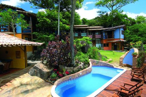 a swimming pool in a yard next to a house at Pousada Villa Da Prainha in Ilhabela