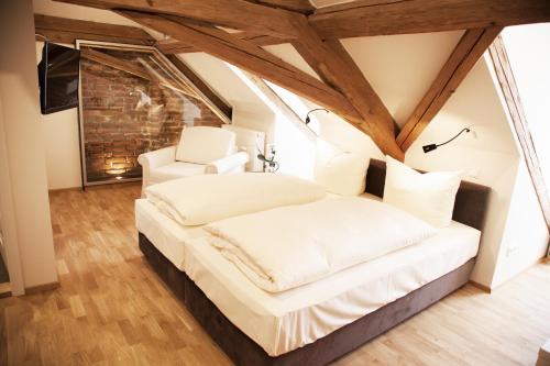 a bedroom with a white bed and two white chairs at Pension Kranzmayr in Sankt Wolfgang