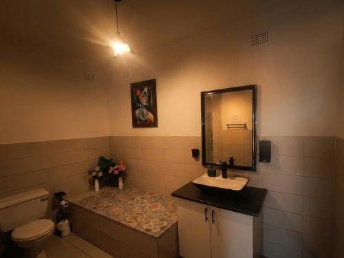 a bathroom with a sink and a toilet and a mirror at Rembrandt - Zur See in Ballito