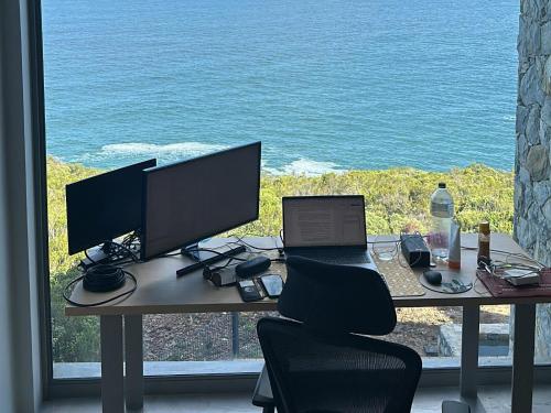 a desk with two computer monitors and a laptop on it at RRoar George in Herolds Bay