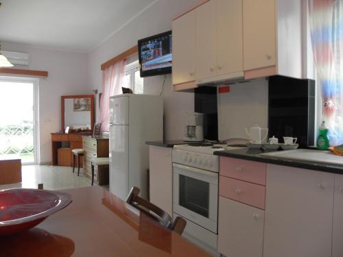 a kitchen with a white refrigerator and a stove at Irida Beach Resort Suites in Kyparissia
