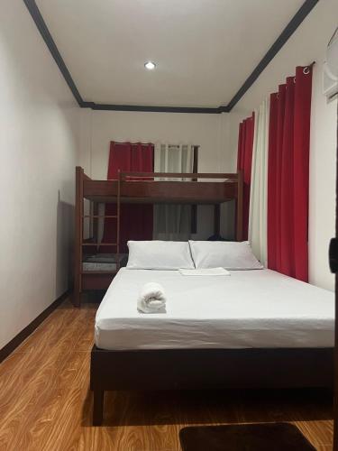 a bedroom with a bed with white sheets and red curtains at Bayakyak Soie Residence in General Luna