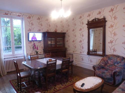 a dining room with a table and chairs and a tv at Maison Commandant Blaison in Lapalisse