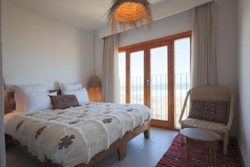 a bedroom with a bed and a chair and a window at Blue Waves Surf House - Anza I in Agadir