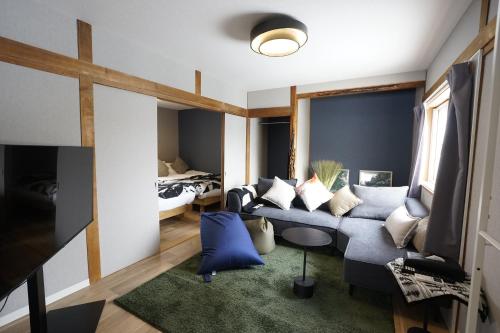 a living room with a blue couch and a bed at Yukimi Nakafurano in Nakafurano