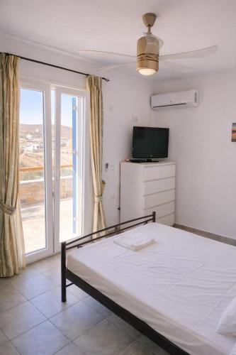 a bedroom with a bed and a tv and a window at Blue Calm House Kythnos in Agios Dimitrios