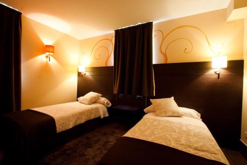 una camera d'albergo con due letti e due luci di Hotel Restaurante Puente Romano a Quincoces de Yuso