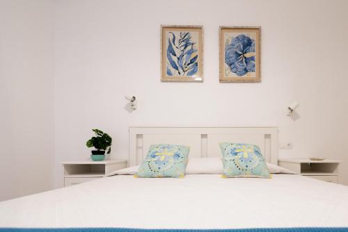 a bedroom with a white bed with two pictures on the wall at Oasis in Costa Calma