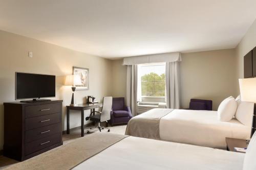 a hotel room with two beds and a desk and a television at Baymont by Wyndham College Station in College Station
