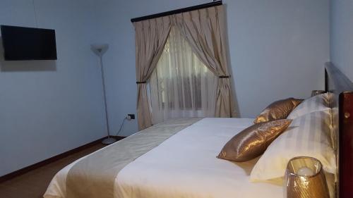 Un dormitorio con una cama con almohadas de oro y una ventana en White City Inn, en Gaborone