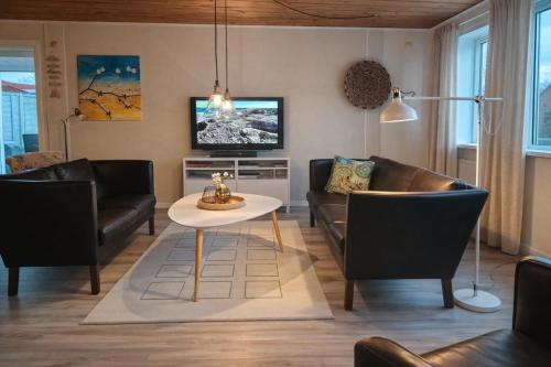 a living room with a couch and a table at Havhuset I Øster Hurup - i byen, ved stranden in Øster Hurup