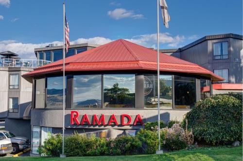 a building with a red roof and a ramada sign at Ramada by Wyndham Kamloops in Kamloops