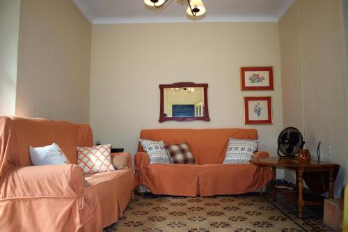 salon z pomarańczową kanapą i lustrem w obiekcie Cortijo Don Rodrigo w mieście El Chorro