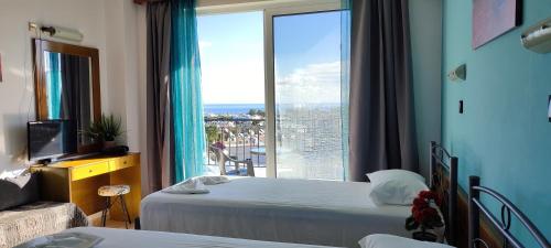 a hotel room with two beds and a large window at Planet View in Faliraki