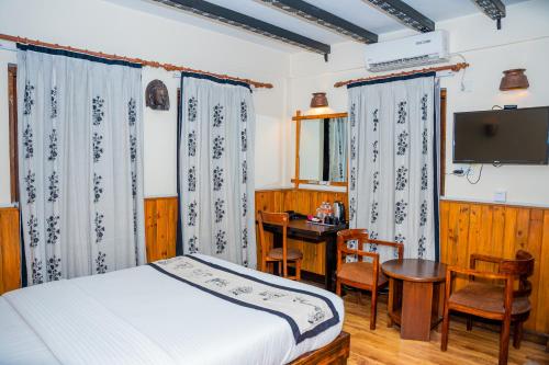 a bedroom with a bed and a desk and a television at Hotel Yechu Comfort Heritage in Bhaktapur