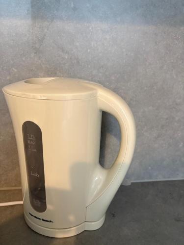 a white coffee cup with a remote control in it at Stylish Studio flat 5, ensuite, kitchenette, Wifi,Parking,Smart TV,Contractors,NHS,Families welcome in West Bromwich