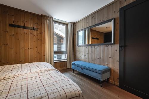 a bedroom with a bed and a blue ottoman and a window at Fyri Tunet Hemsedal in Hemsedal