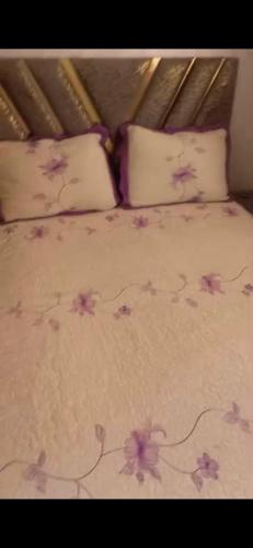 a bed with pink flowers on the sheets and pillows at Jawhara zarka in Saïdia