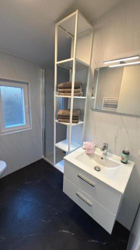 a bathroom with a white sink and a towel rack at Casa del Carmen airco, privé hottub en sauna, WiFi and 2 bedrooms in Heinkensand
