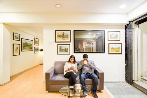 a man and woman sitting on a couch in a living room at FabHotel White Ridge Chaitanyapuri in Hyderabad
