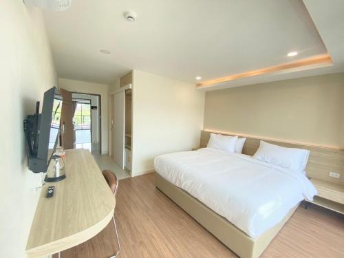 a bedroom with a bed and a desk and a television at Pinotel Prachuap - โรงแรมพิโนเทล ประจวบ in Prachuap Khiri Khan