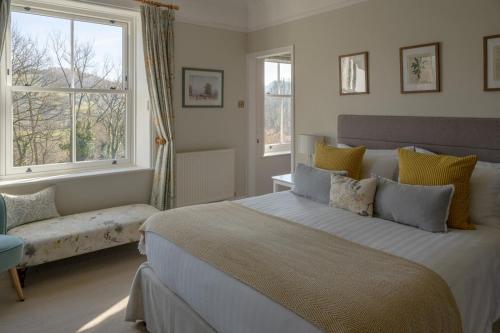 a bedroom with a large bed and two windows at Broom House at Egton Bridge in Egton
