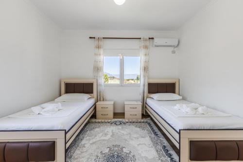 two beds in a room with a window at Castle Serenity Home 3BR with Free Parking by PikHost in Gjirokastër