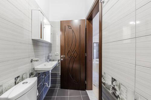 a bathroom with a wooden door and a sink at Castle Serenity Home 3BR with Free Parking by PikHost in Gjirokastër