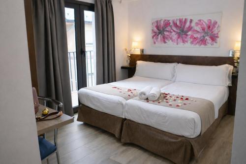 una camera da letto con un grande letto con petali di rose rosse sopra di Aston Hotel ad Andorra la Vella