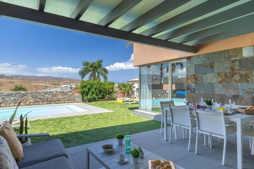 a patio with a table and chairs and a pool at Yellow Sunshine 8 by VillaGranCanaria in Salobre