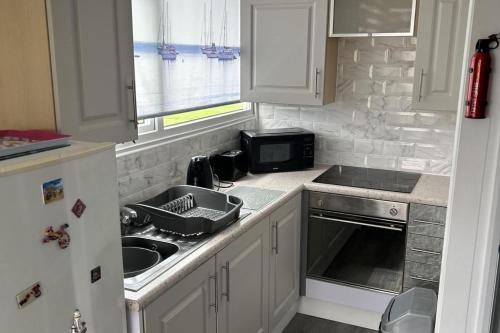 a kitchen with a sink and a microwave at Cozy Seaside Chalet in Bridlington in Bridlington