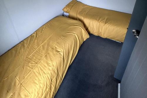 a yellow bed in a corner of a room at Cozy Seaside Chalet in Bridlington in Bridlington