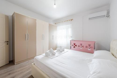 a bedroom with a large white bed with a pink headboard at Hometown Apartment by PikHost in Gjirokastër