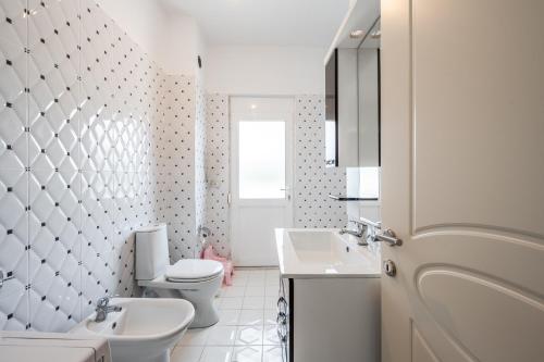 a white bathroom with a toilet and a sink at Hometown Apartment by PikHost in Gjirokastër