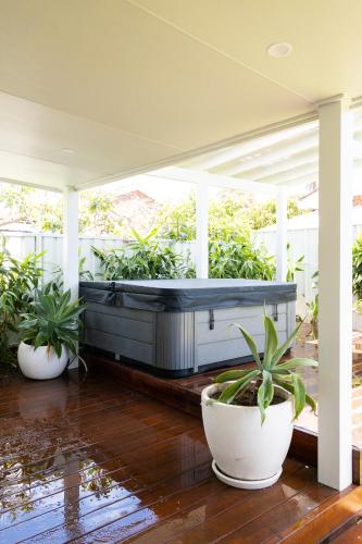 a hot tub on a porch with potted plants at Studio11 - Vincentia in Vincentia