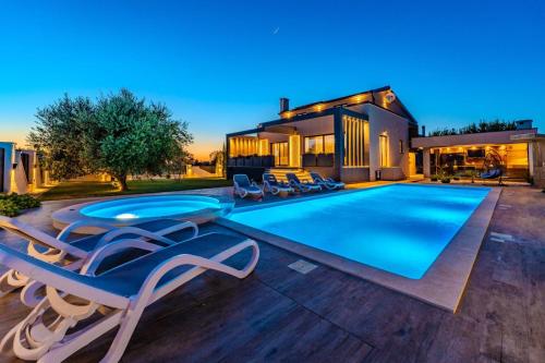 a swimming pool with chairs and a house at Villa Klara in Privlaka