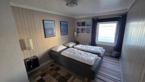 a small bedroom with two beds and a window at Solodden, Authentic rorbu in Lofoten in Sennesvik
