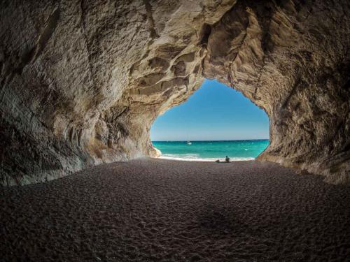a cave on a beach with the ocean behind it at La Terrazza In Centro Dorgali in Dorgali
