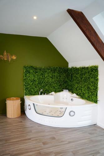 a bath tub in a room with a green wall at Jungle Room - Studio avec spa privé in Quéven