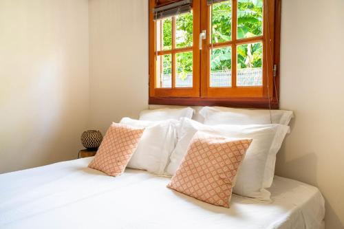 a bedroom with a white bed with a window at Bungalow Kaz Mendé in Sainte-Anne