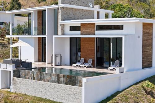 a house with a swimming pool and two chairs at Passot Hills - Villas Premium in Nosy Be