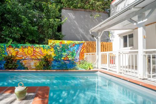 a swimming pool with a colorful wall next to a house at Villa Kaz a Ramon in Port-Louis