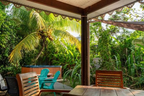 a patio with chairs and a table and a palm tree at Bungalow Kaz Graj in Sainte-Anne